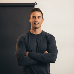 Portrait of Tyler Vance, a fit man in a dark performance top, looking confident, with a clean cream background.